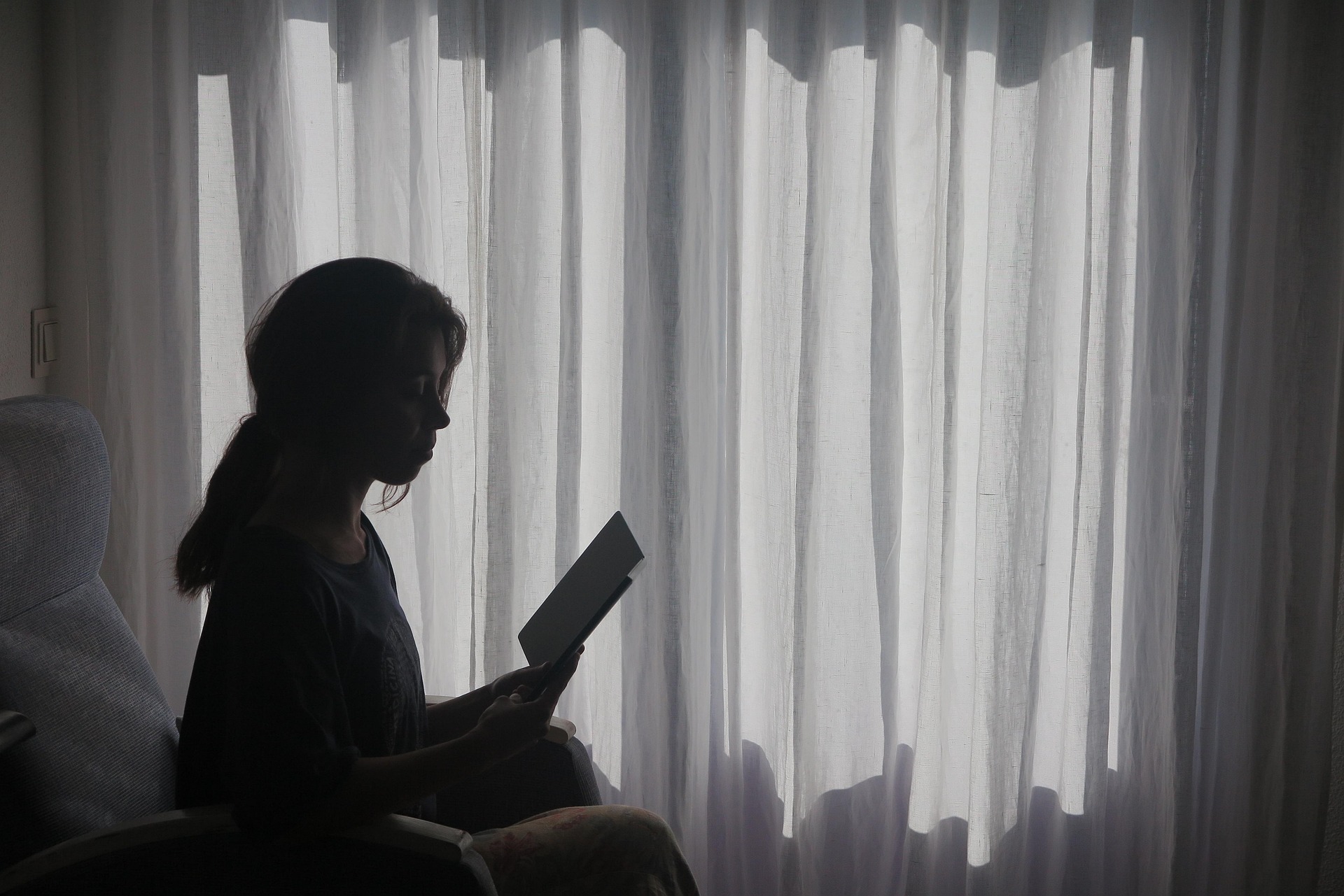 Woman reading in the curtains